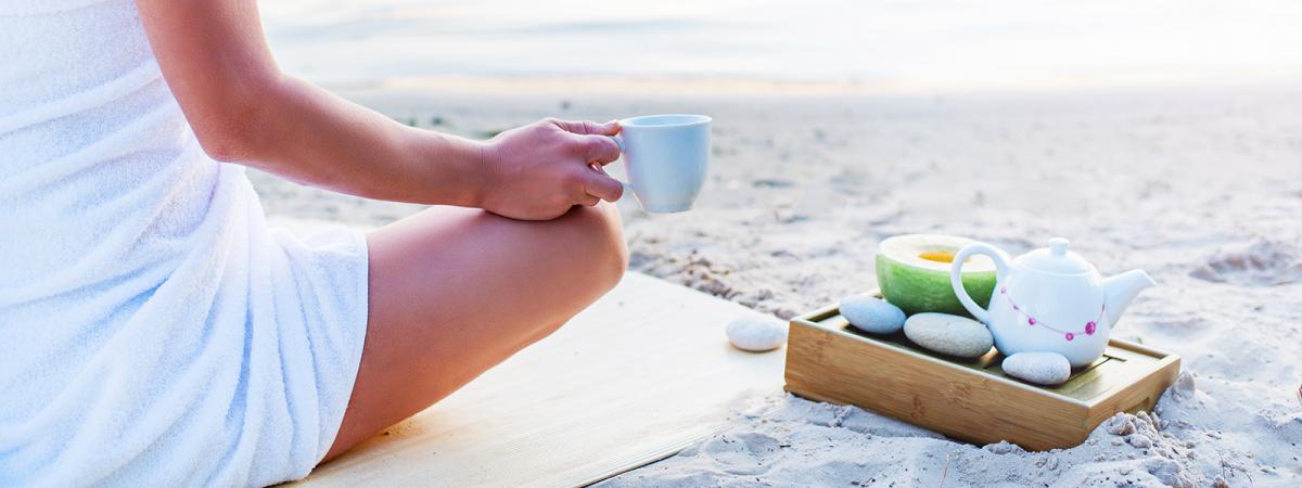 Una donna sorseggia caffè sulla spiaggia
